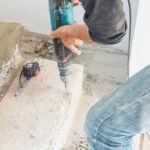 Worker drilling into a concrete floor with a rotary hammer in Surrey, BC