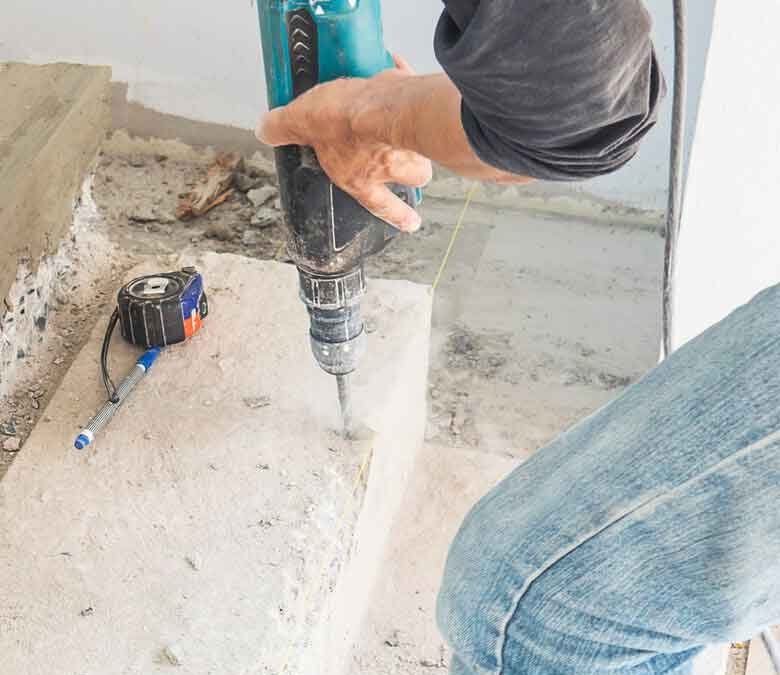 Worker drilling into a concrete floor with a rotary hammer in Surrey, BC