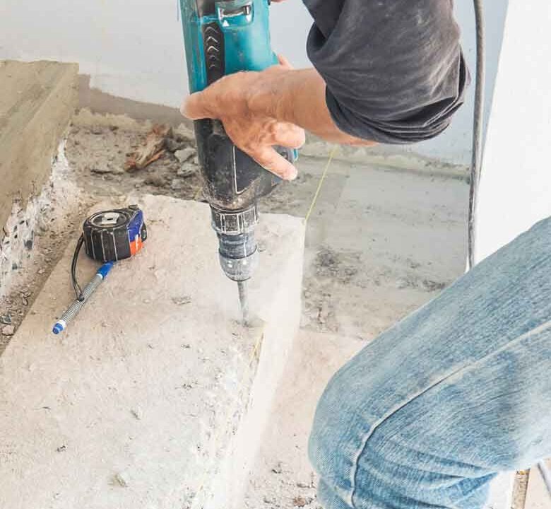 Worker drilling into a concrete floor with a rotary hammer in Surrey, BC