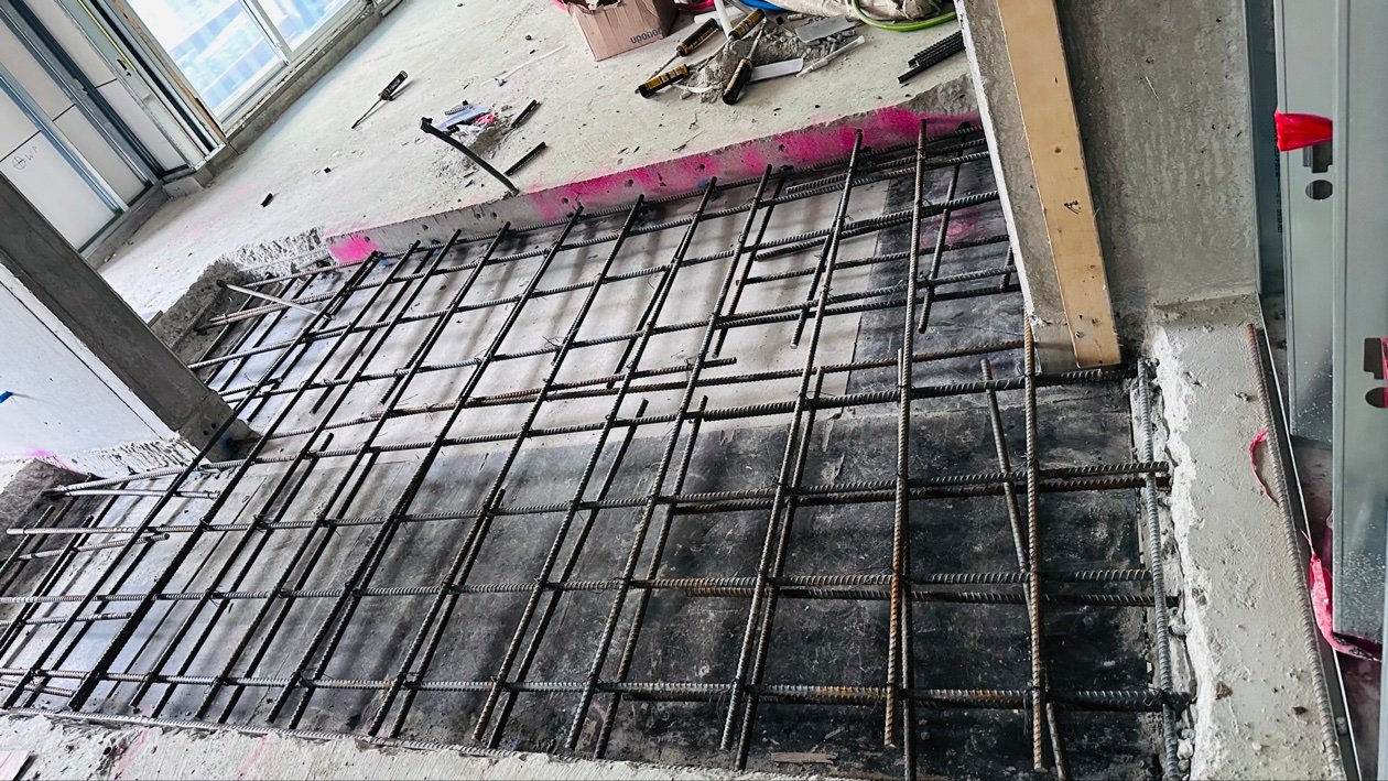Inserting steel rebar into an epoxy-filled dowel hole in existing concrete